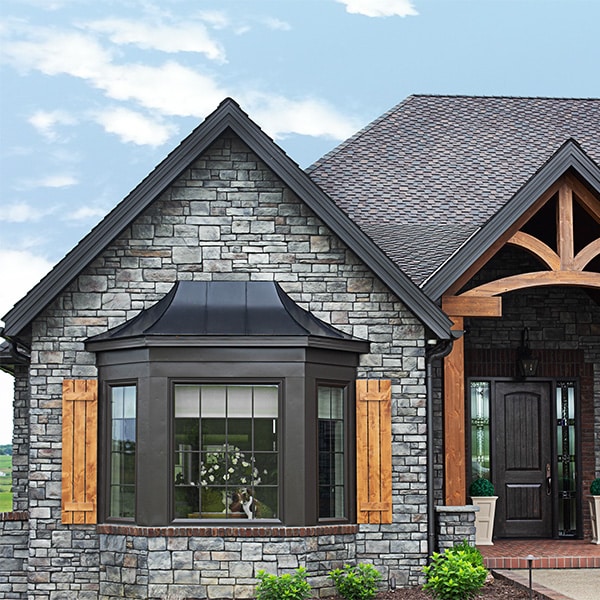 black bay window on rustic stone craftsman house