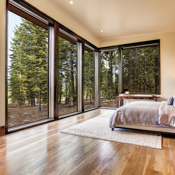 tall floor-to-ceiling picture windows with black frame inside light-colored bedroom