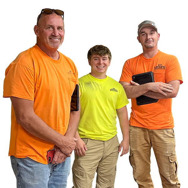 three adult males wearing work shirts and pants smiling at camera