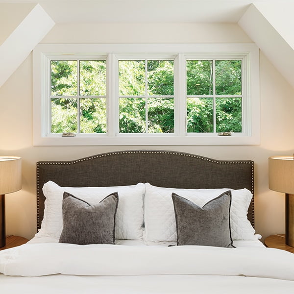 three white four-light windows above large bed