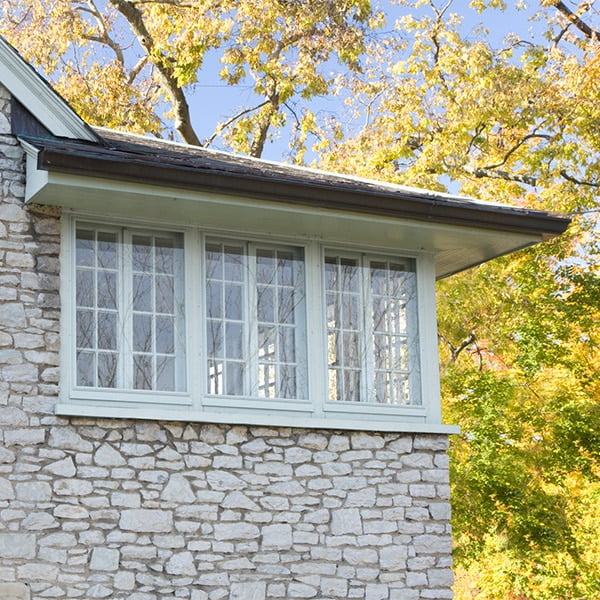 white storm windows on stone sided house