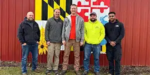 newsletter-thumbnail-2024-02 five adults in fall clothing posing in front of a wall mural