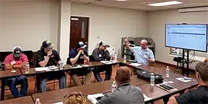 newsletter-thumbnail-2024-07 adult man gives presentation to conference room of adults