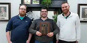 newsletter-thumbnail-2024-12 three adults pose with bowling plaque