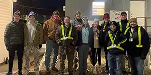 large group of adults and teenagers pose for group photo wearing winter clothing