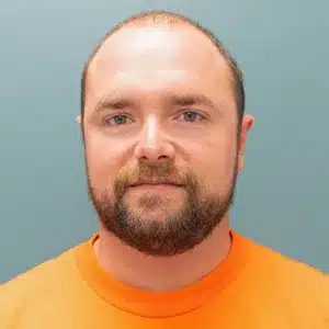 michael-klaus adult male with thinning brown hair and brown facial hair wearing an orange shirt