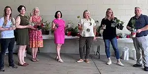 several adults in professional attire holding plants