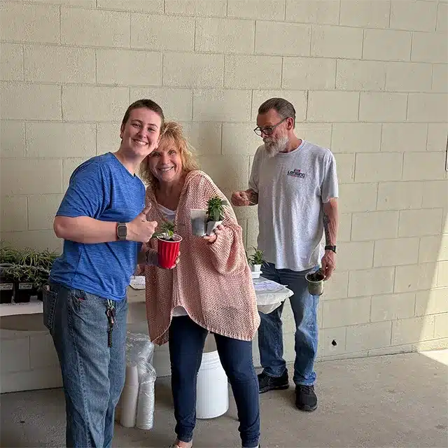 two women and one man looking at plants