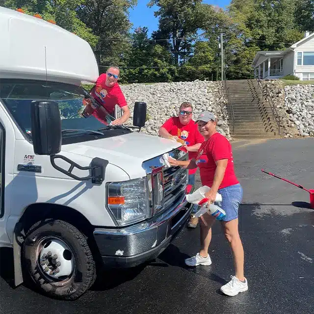 three adults washing a transport bus