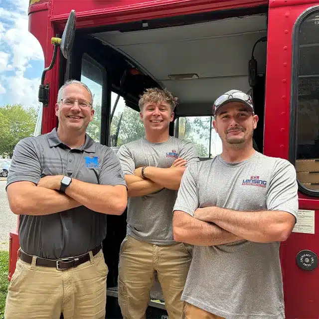 three adults standing next to red food truck
