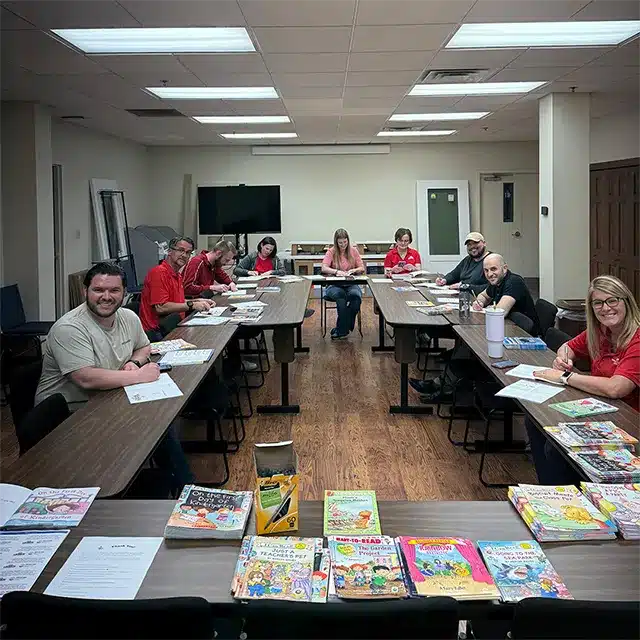a conference room full of business professionals signing books