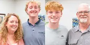 four people standing next to each other smiling