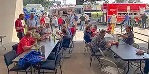 a large group of adults waiting on food at food trucks
